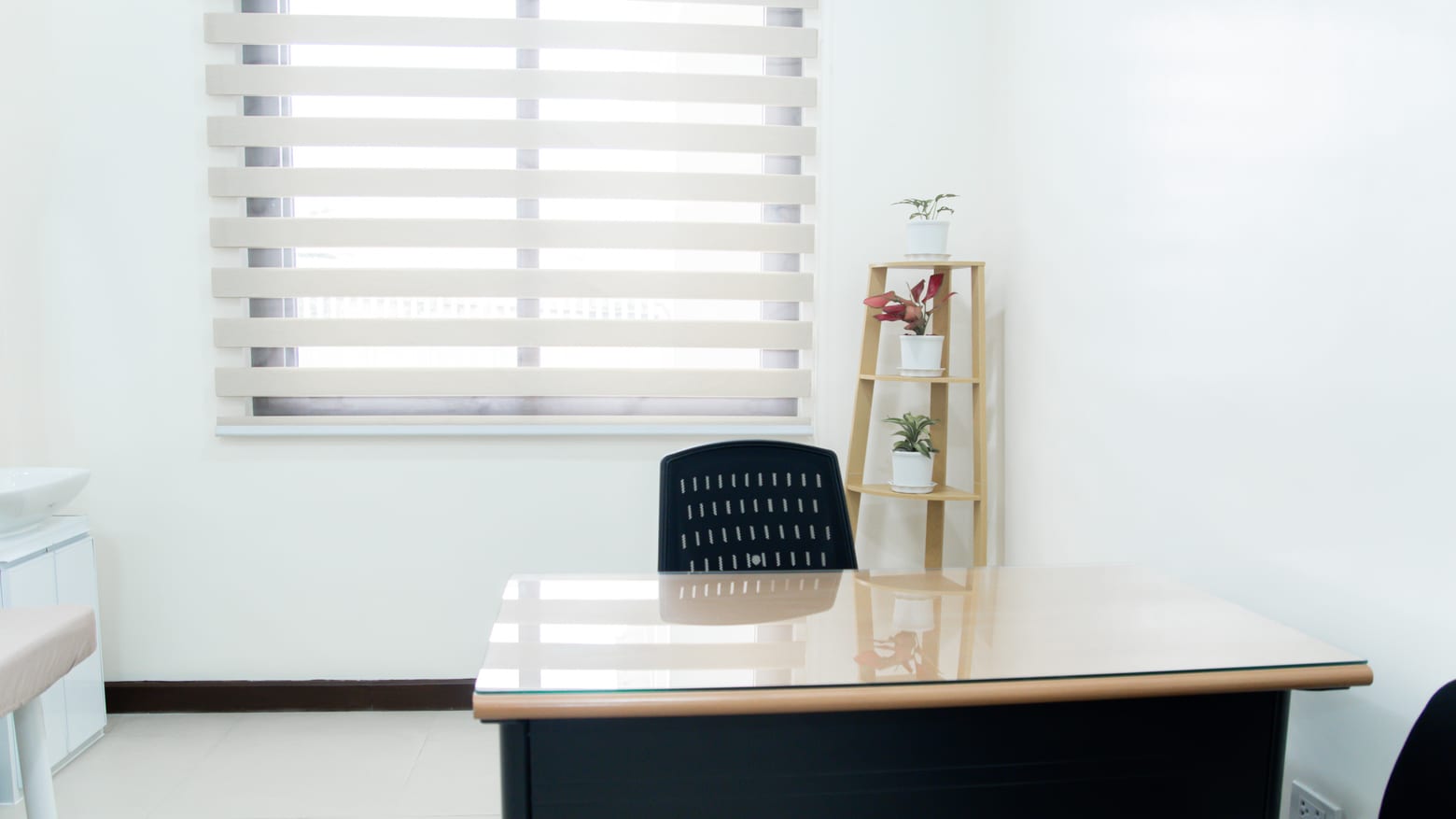 The clinic doctor listening to a patient across the consultation-room desk.