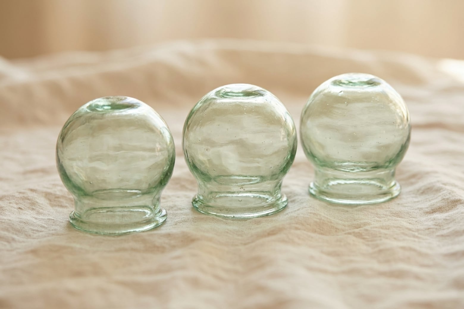 Three glass cupping cups resting on folded linen.